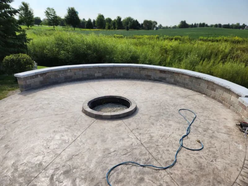 Circular stamped concrete patio with fire pit and curved stone seating wall